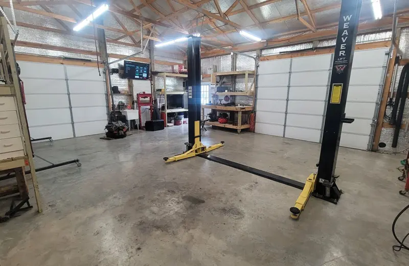 The open shop floor with a two-post lift, tool chests and shelving
