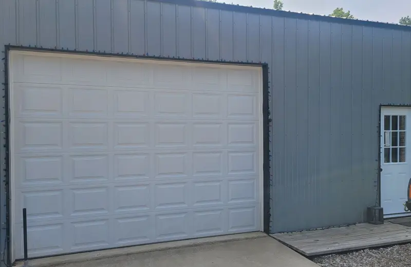 The outside of the shop with its roll-up bay door and side entry